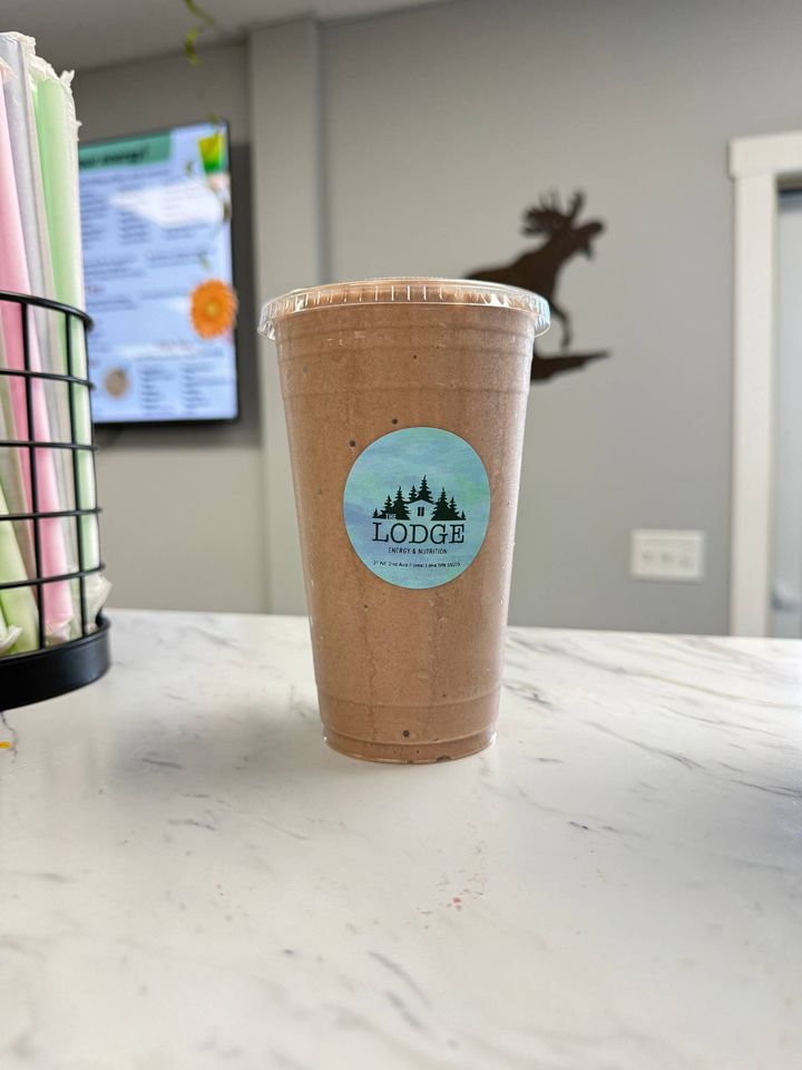A chocolate protein shake in a Lodge cup on the counter, with the moose sign on the wall behind it